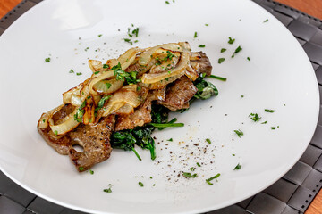 Grilled Liver with Onions closeup in the bowl served with bread on the table.