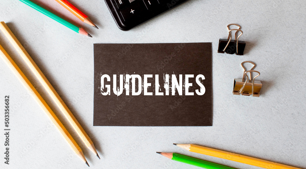 Poster white paper with the text guidelines is attached to the wooden background with a black button.