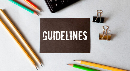 White paper with the text GUIDELINES is attached to the wooden background with a black button.
