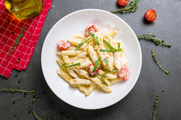 Penne four cheese with mini tomatoes top view on grey table