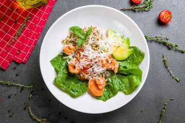 salad quinoa with salmon and avocado with parmesan and spinach top view on grey table