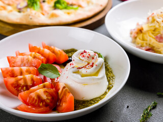 Salad with buratta cheese and tomatoes on bowl on grey table macro close up