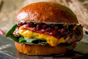 Black Burger with meat, cheese and spinach with bacon and cherry  on the board extreme macro close up