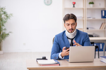 Obraz premium Young neck injured male employee sitting in the office