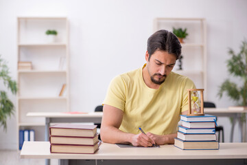 Young male student preparing for exams in time management concep