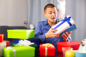 Cheerful adult man opening box with gift, celebrating his birthday