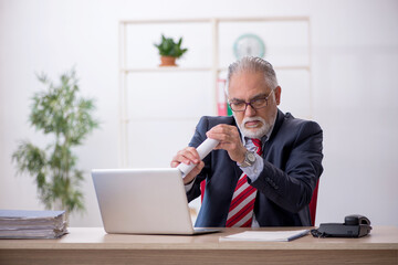Fototapeta premium Old male employee working in the office