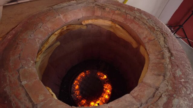 Tandoor. Inside oven, fire burns and flat bread is baked on walls. Khachapuri. Georgian cuisine. Bakery or bread production. Work from gas. Culture of Georgian or Oriental cuisine.