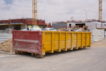 Construction waste in a Huge Overloaded dumpster. Waste metal tank container filled with...