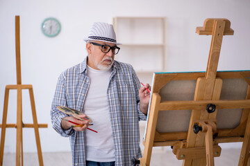 Old man enjoying painting at home