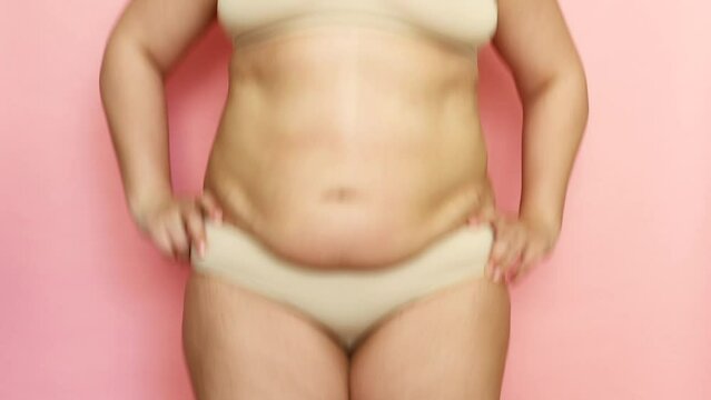 Unrecognizable fat woman with overweight bouncing and jumping. Excessive fat on stomach. Concept of reducing abdomen and forming healthy abdominal muscles. Subcutaneous fat breakdown. Pink background