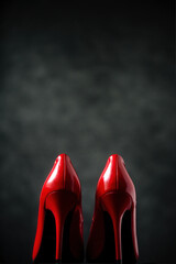 bright red high-heeled shoes stand on a dark background
