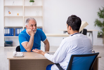 Obraz premium Old male patient visiting young male doctor