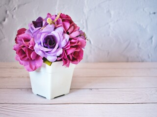 Artificial purple rose flowers bouquet in pot on table ,copy space for text or writing ,pretty texture background or wallpaper ,mother's day ,still life ,women's day festive background ,spring flora