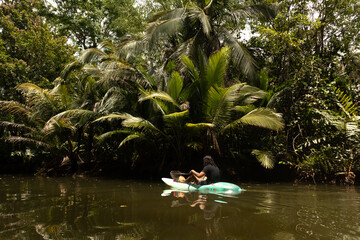 boy with long hair riding a kayak on the river in the middle of tropical nature