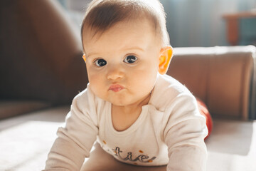Fototapeta premium Caucasian baby lying on stomach with serious face looking at camera. Family care. Baby care.