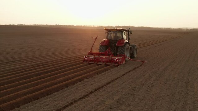  Red tractor working in agriculture field at sunset. Tractor prepares the field for sowing. Growing wheat in an agricultural field. April 2022, Prague, Czech Republic