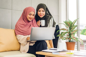 Young two smiling happy beautiful asian muslim woman relaxing using laptop computer working and meeting analyzing discussing strategy with startup project plan and brainstorm at home