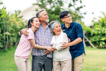 Portrait enjoy happy smiling love multi-generation asian big hug family.Senior mature father and elderly mother with young adult woman and son outdoor in park at home.insurance concept