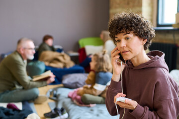 Young woman with dark short curly hair communicating on mobile phone in front of camera against...