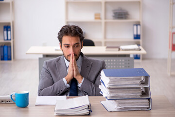 Naklejka premium Young male employee and too much work in the office