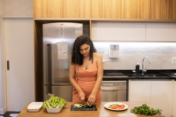 Mulher brasileira cortando pepino para salada