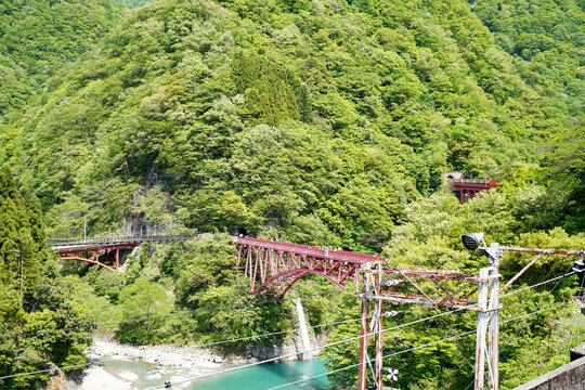 赤い鉄橋の背景に広がる美しいい自然の山々の美しい風景写真・黒部峡谷鉄道・黒部峡谷・富山県観光地