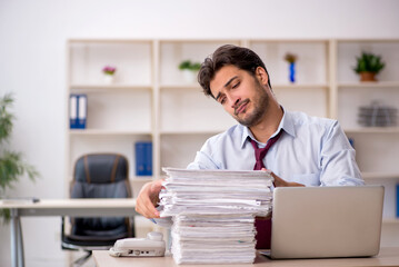 Young male employee and too much work in the office