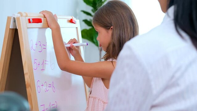 Close Up Shot Of Adorable Girl Using Marker To Write On Whiteboard Answering Questions In Math Lessons To Teacher In Front Of Classroom Learning With Fun At Kindergarten School, Concept Of Learning