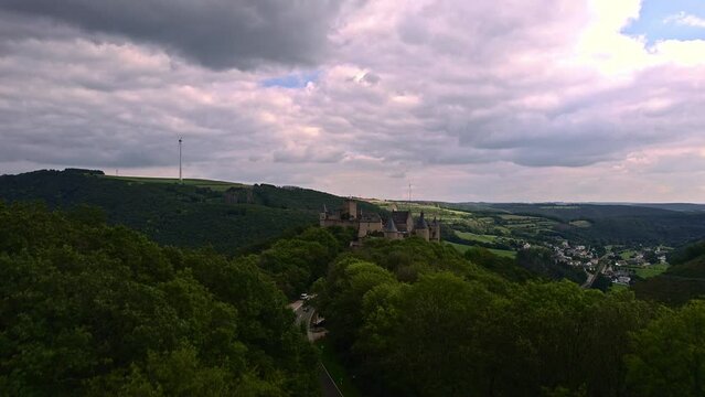 View from the top of the mountain, drone rises from the woods aiming at beautiful romantic castle of Bourscheid, view of the mountain and the valley, view of the village, forests and meadows