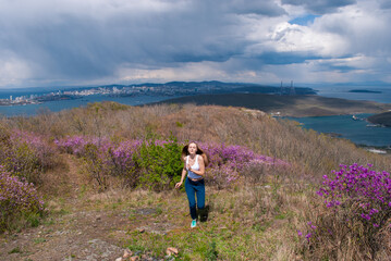 Beautiful girl in a spring meadow with Rhodod&eacute;ndron. 