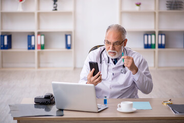 Old male doctor in telemedicine concept