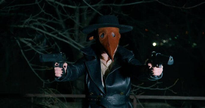 Criminal woman in plague doctor mask walks shooting with guns in turn. Dangerous killer attacks victim using weapon on street at dark night