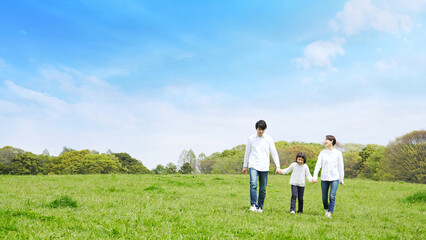 青空の草原を歩く家族　環境　子育て