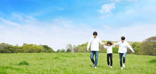 青空の草原を歩く家族　環境　子育て