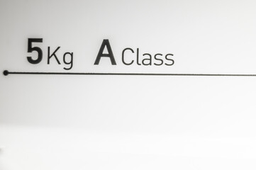 Sign of the maximum load of dirty laundry for washing in the washing machine and its energy efficiency class. Inscriptions on the control panel of the washing machine. Selective focus