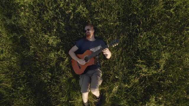 Playing the guitar in the grass, aerial view