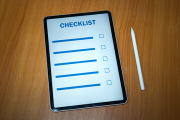 A safety checklist blank form which is opened in tablet and placed with digital pen on the table, prepared for safety inspection work. Working in paperless concept, object photo. Selective focus.