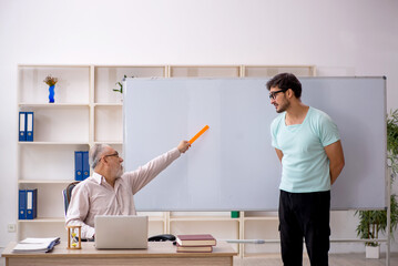 Old male teacher and young male student in the classroom