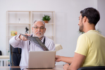 Young male doctor visiting old male doctor radiologist