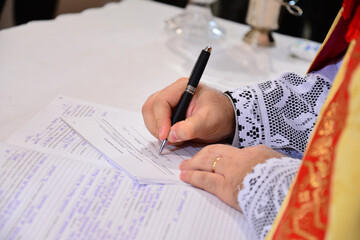 close-up of a priest signing a document, contract signing, marriage contract signing, priest's...