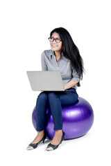 Young businesswoman using a laptop on yoga ball