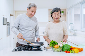 Aged man helping his wife to cooking at home