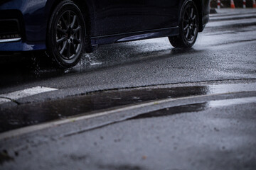 Obraz na płótnie Canvas 雨の道を走る車　A car running on a rainy road