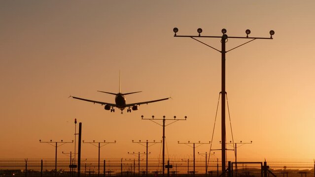 Plane flying over head, landing at airport at sunset or sunrise, RED camera footage background. Airplane approaching and landing at early morning in Los Angeles, California, United States of America