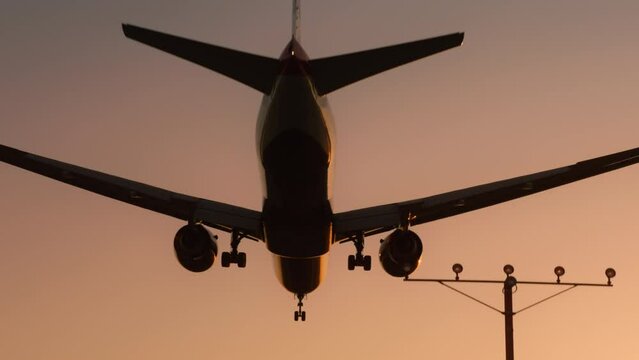 Glide path with blinking lights and golden sun above horizon line, USA Los Angeles. Plane flying over head, landing at airport at sunset or sunrise. Cinematic travel background with copy or text space