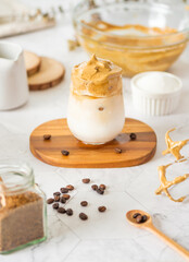 Fototapeta na wymiar Dalgona coffee with fluffy cream served on wood tray with ingredeint .Homemade trendy beverage menu on social media