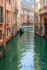 Narrow canal with gondola in Venice, Italy.