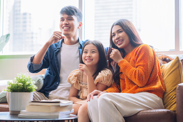 fun and joyful exiting moment asian family parent and daughter sit together watching online streaming concert together on sofa couch in living room at home,happiness family dance moving hand cheerful