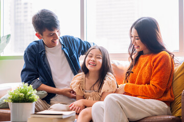 cheerful asian family play tickle parent daughter laugh smiling fun happiness together on sofa in living room,relax casual family activity after packing stuff for home moving finish home moving ideas  - obrazy, fototapety, plakaty